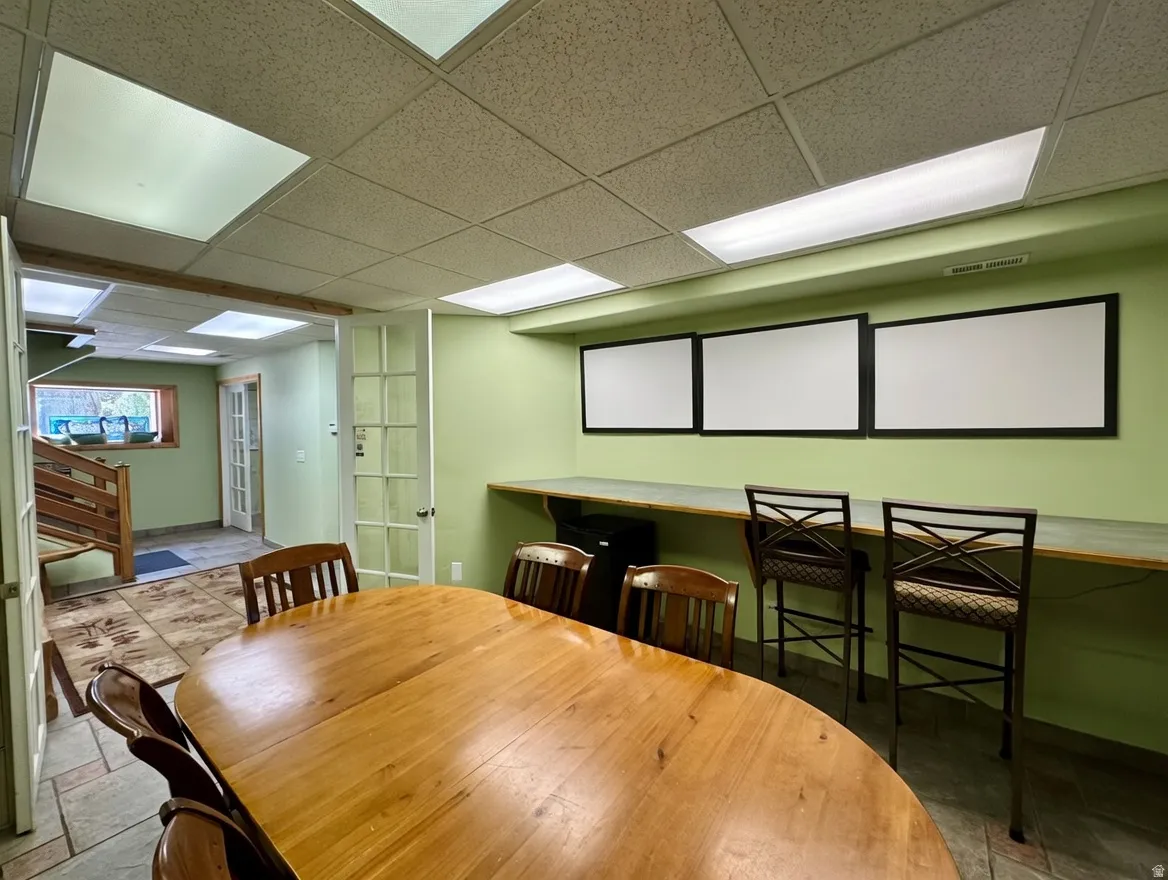 Dining room with a drop ceiling, stone tile floors, and french doors