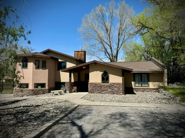 View of front of house featuring stucco siding, a chimney, and stone siding