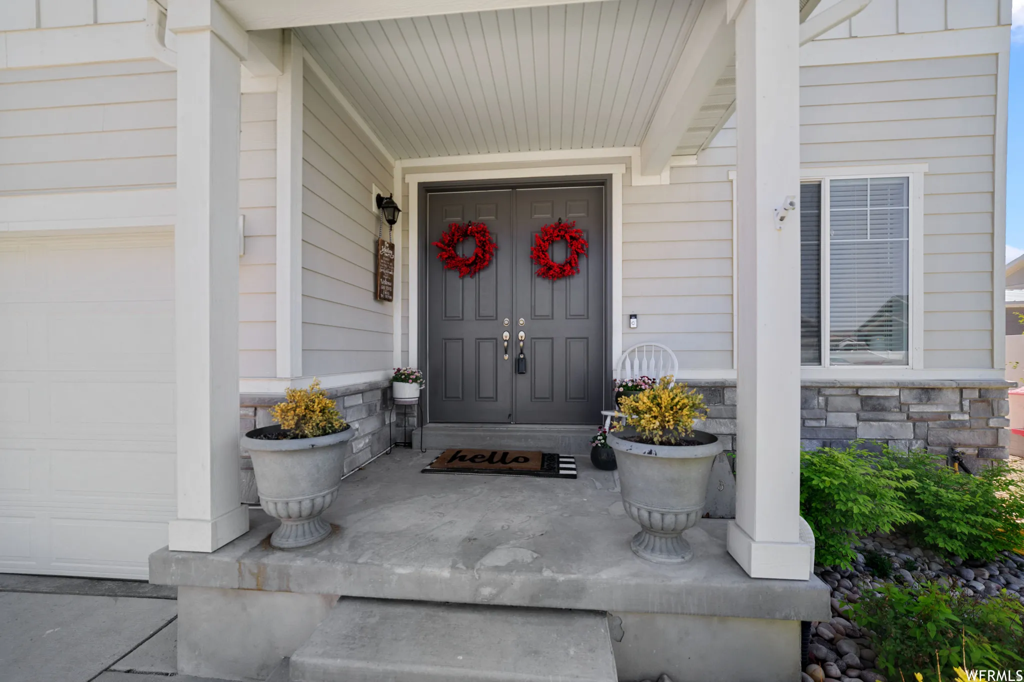 View of exterior entry featuring covered porch, stone siding, and a garage