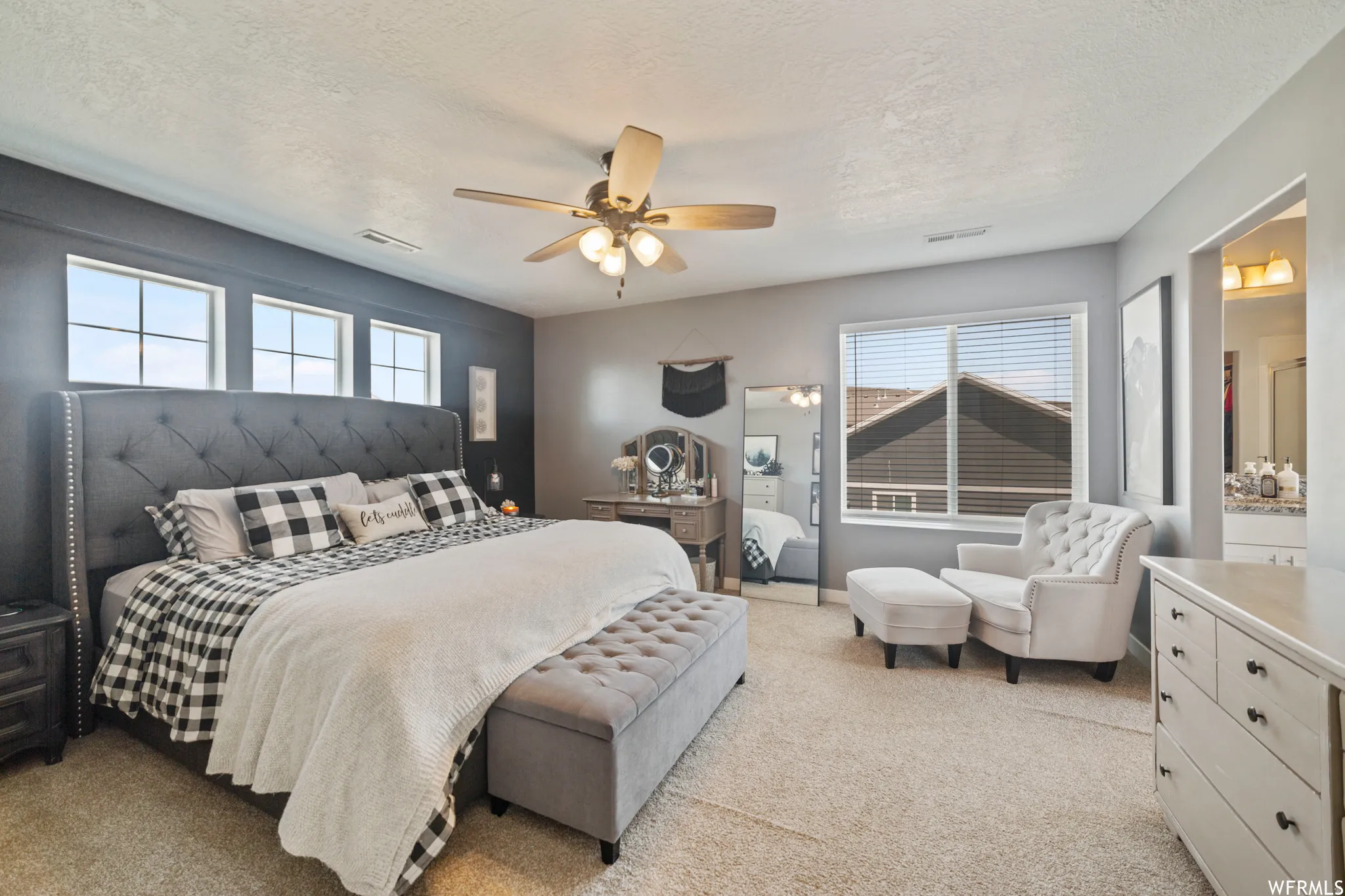 Bedroom with light carpet, a ceiling fan, a textured ceiling, and connected bathroom