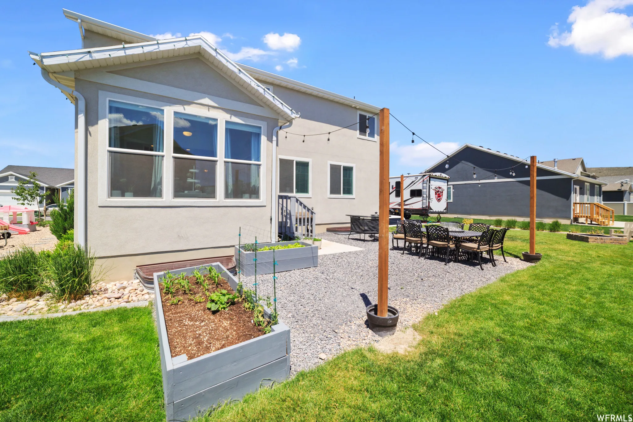 Back of house featuring a garden, a patio, a yard, and stucco siding