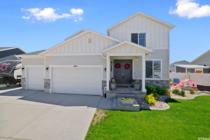 View of front of property with board and batten siding, stone siding, a garage, and driveway