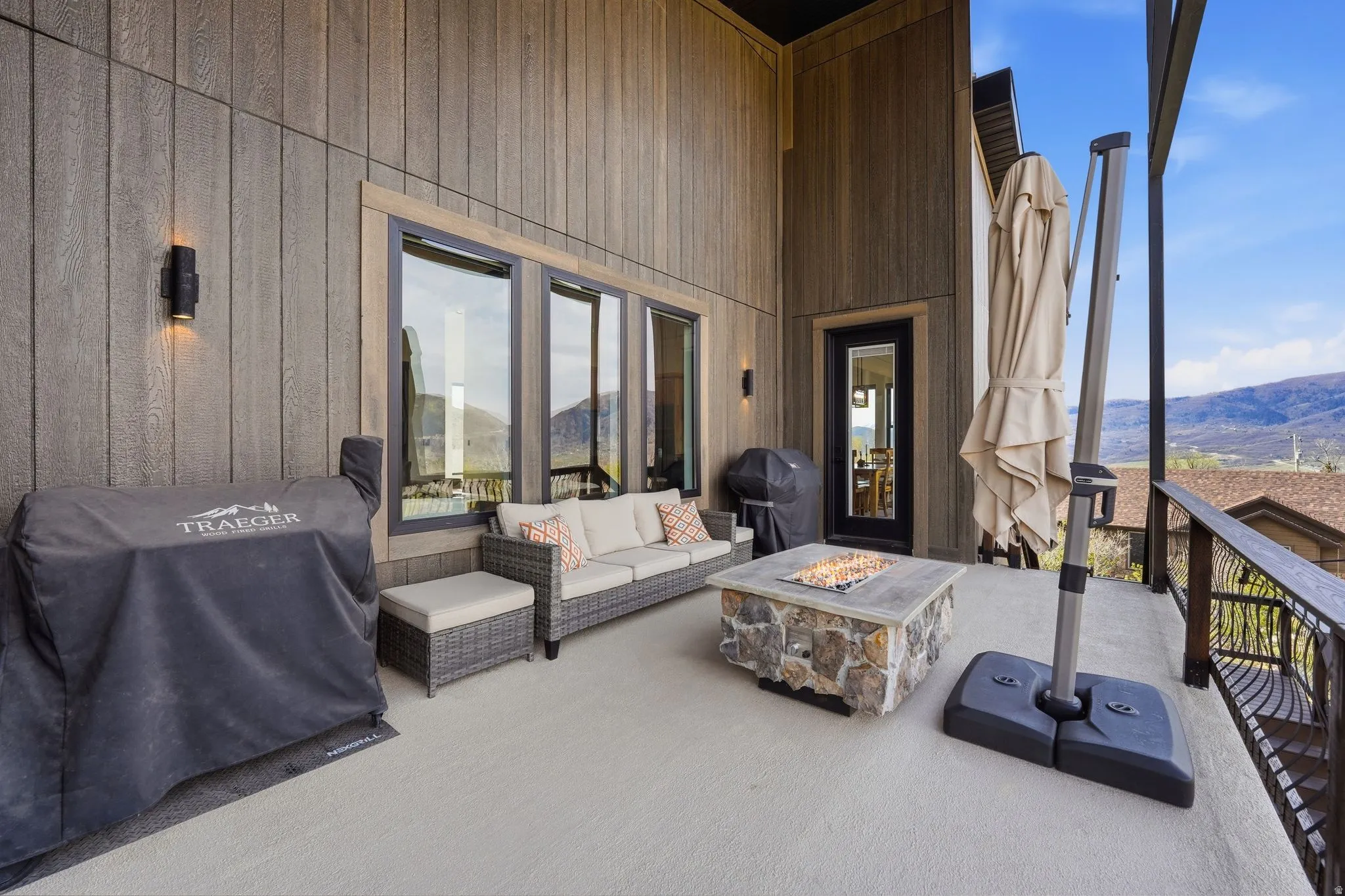Wooden terrace with a mountain view, area for grilling, an outdoor living space with a fire pit, and a patio