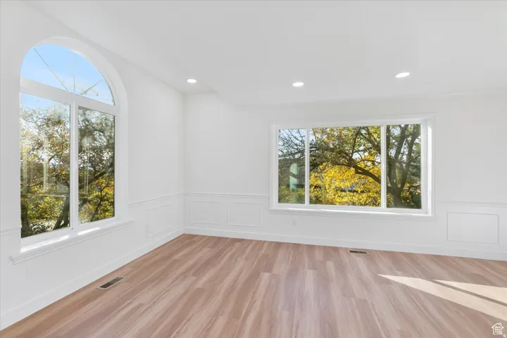Empty room featuring light wood finished floors, recessed lighting, and wainscoting