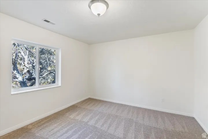 Empty room with light colored carpet and baseboards