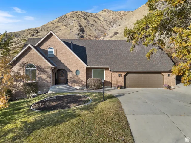 View of front of home featuring brick siding, concrete driveway, a mountain view, and an attached garage