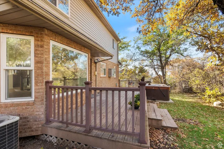 Deck with a hot tub and a yard