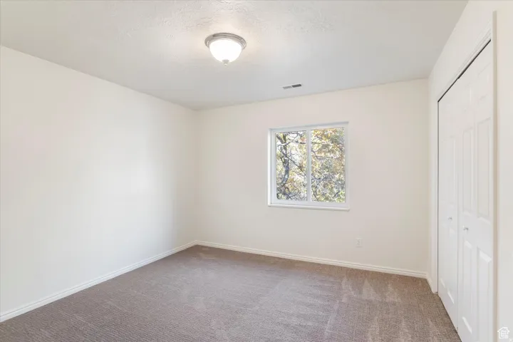 Unfurnished bedroom with a closet, carpet floors, and a textured ceiling
