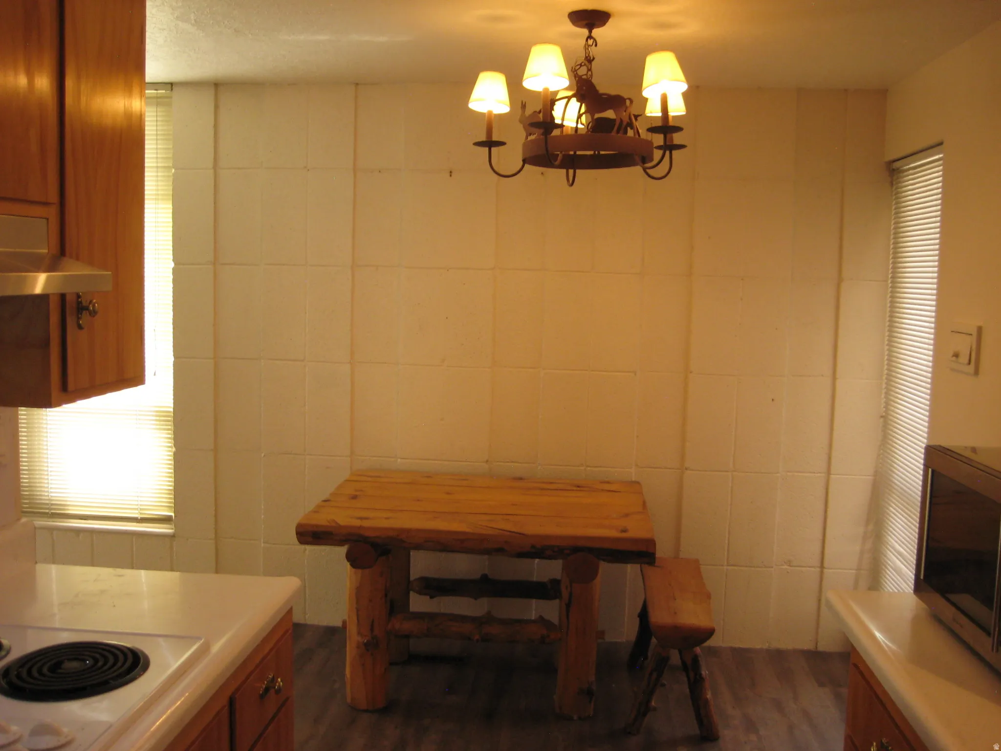 Dining space with suspended lighting, dark wood-style floors, and tile walls