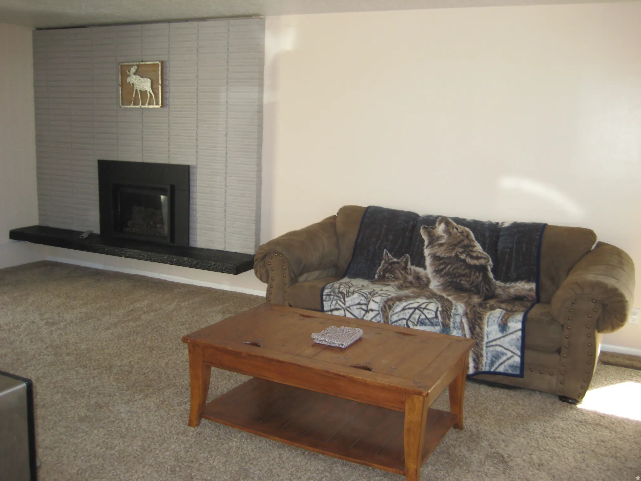 Living area featuring light colored carpet and a fireplace