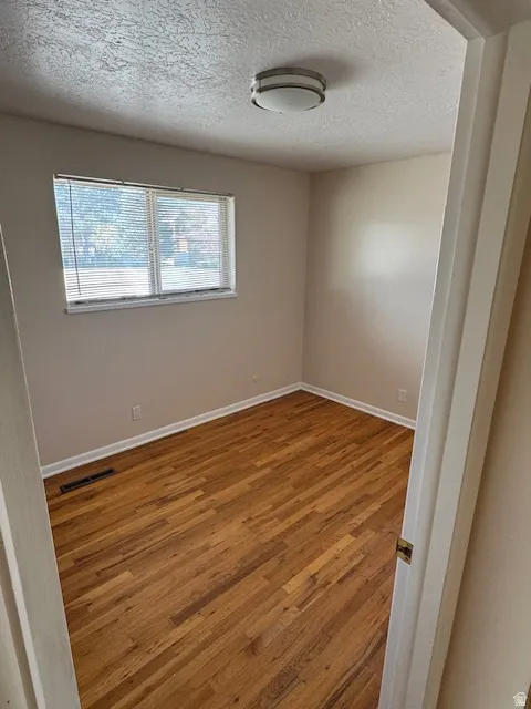 Unfurnished room featuring wood-type flooring and a textured ceiling