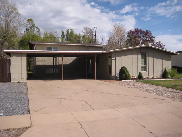 Mid-century modern home featuring driveway, board and batten siding, and an attached carport