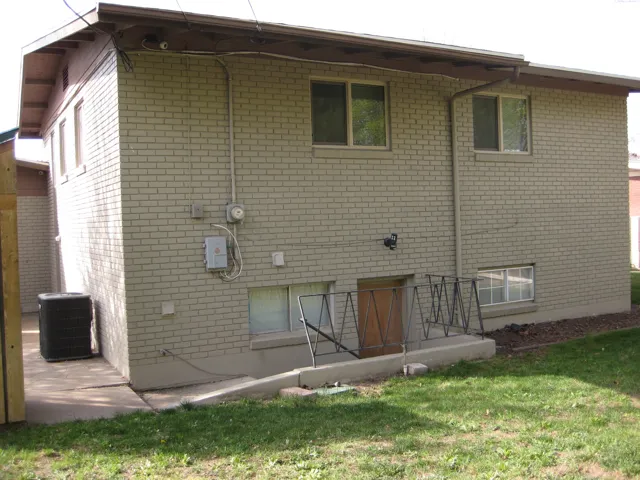 Back of house featuring brick siding and a lawn