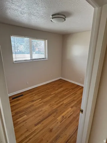 Unfurnished room featuring wood-type flooring and a textured ceiling