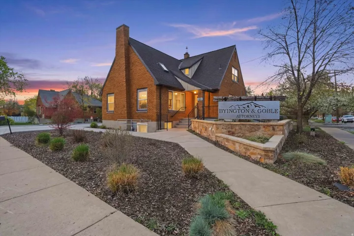 View of front of office with a chimney, brick siding, and a shingled roof