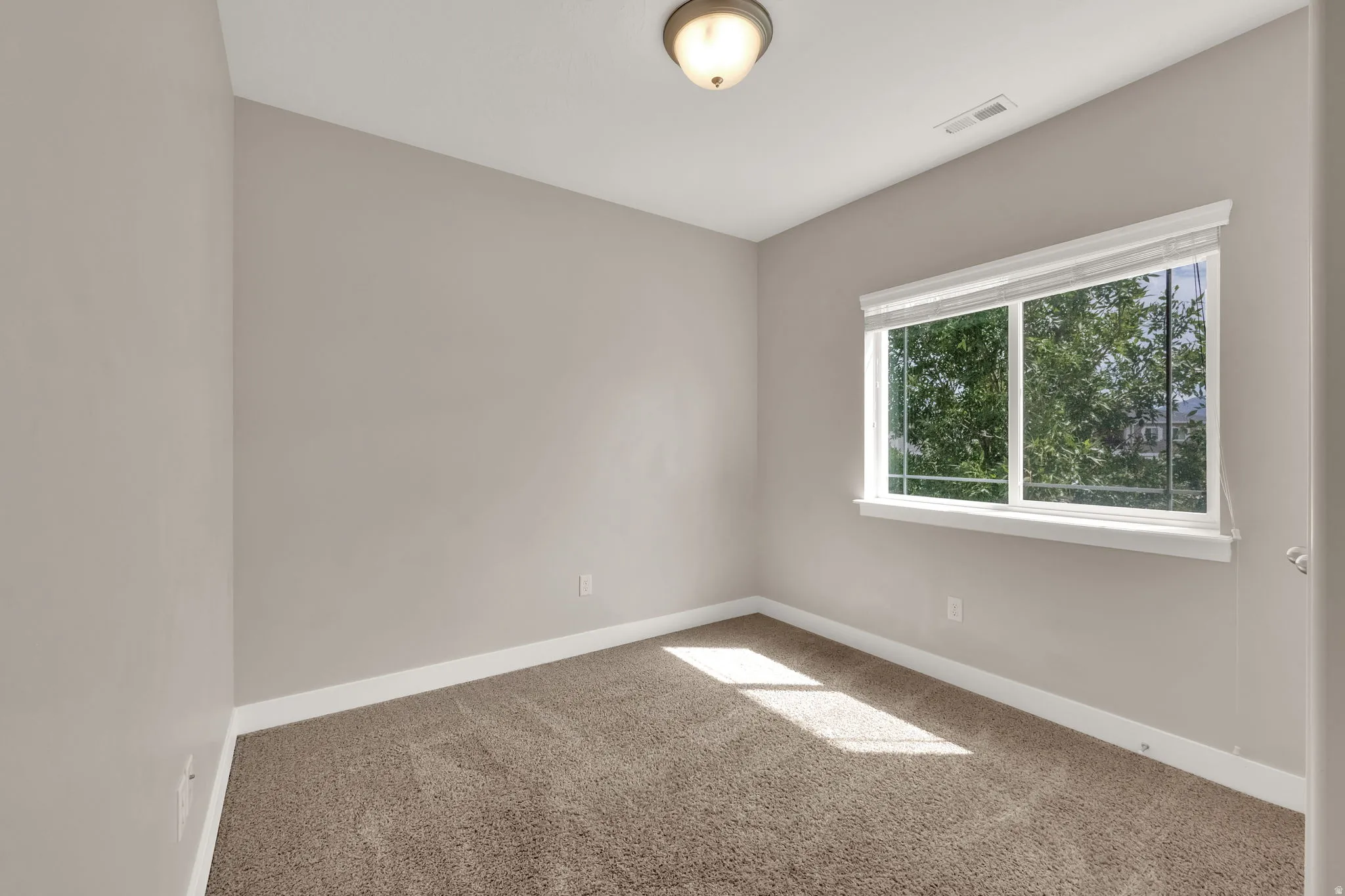Spare room with baseboards and light colored carpet