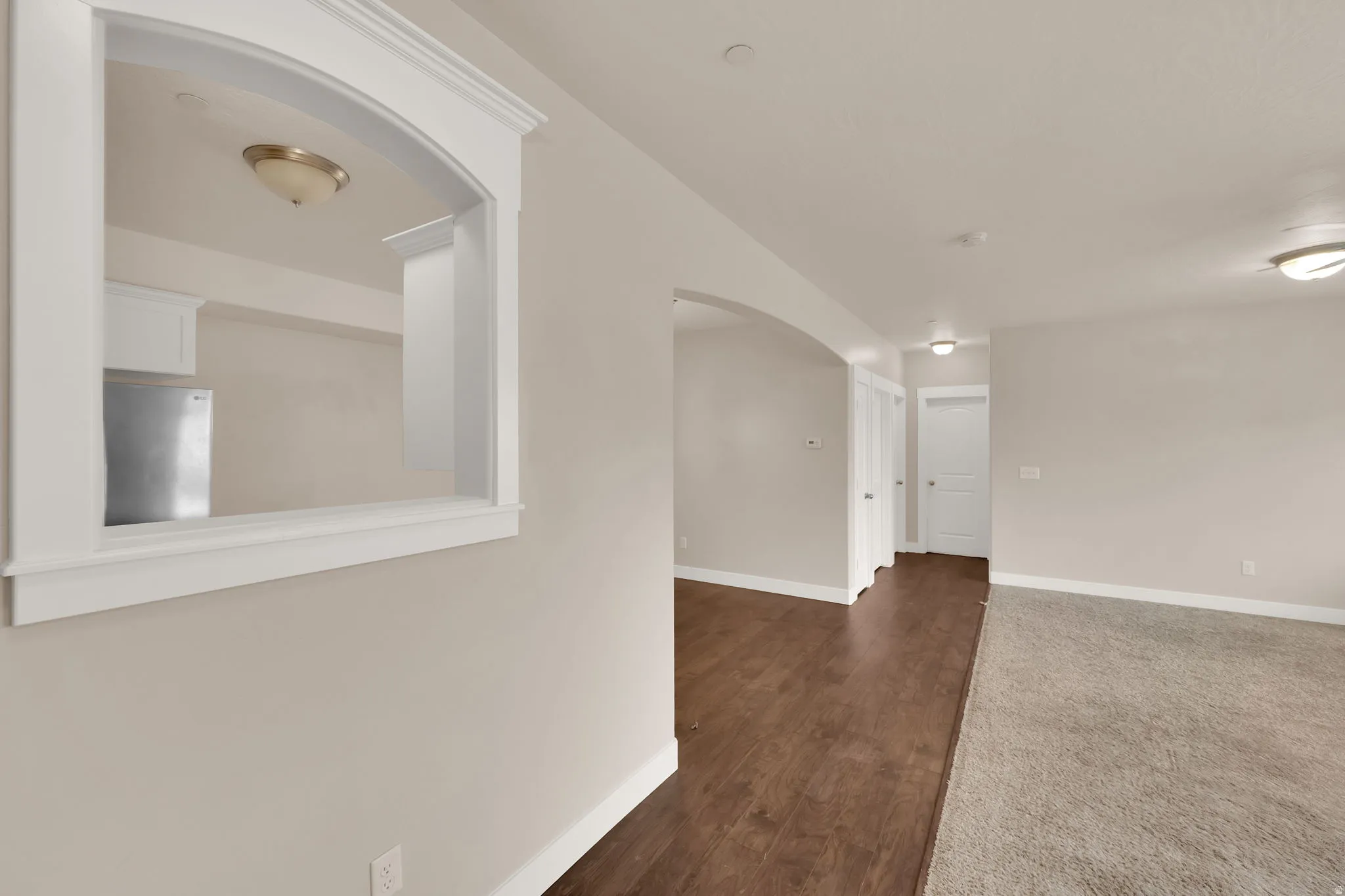 Unfurnished room with arched walkways and dark wood-type flooring
