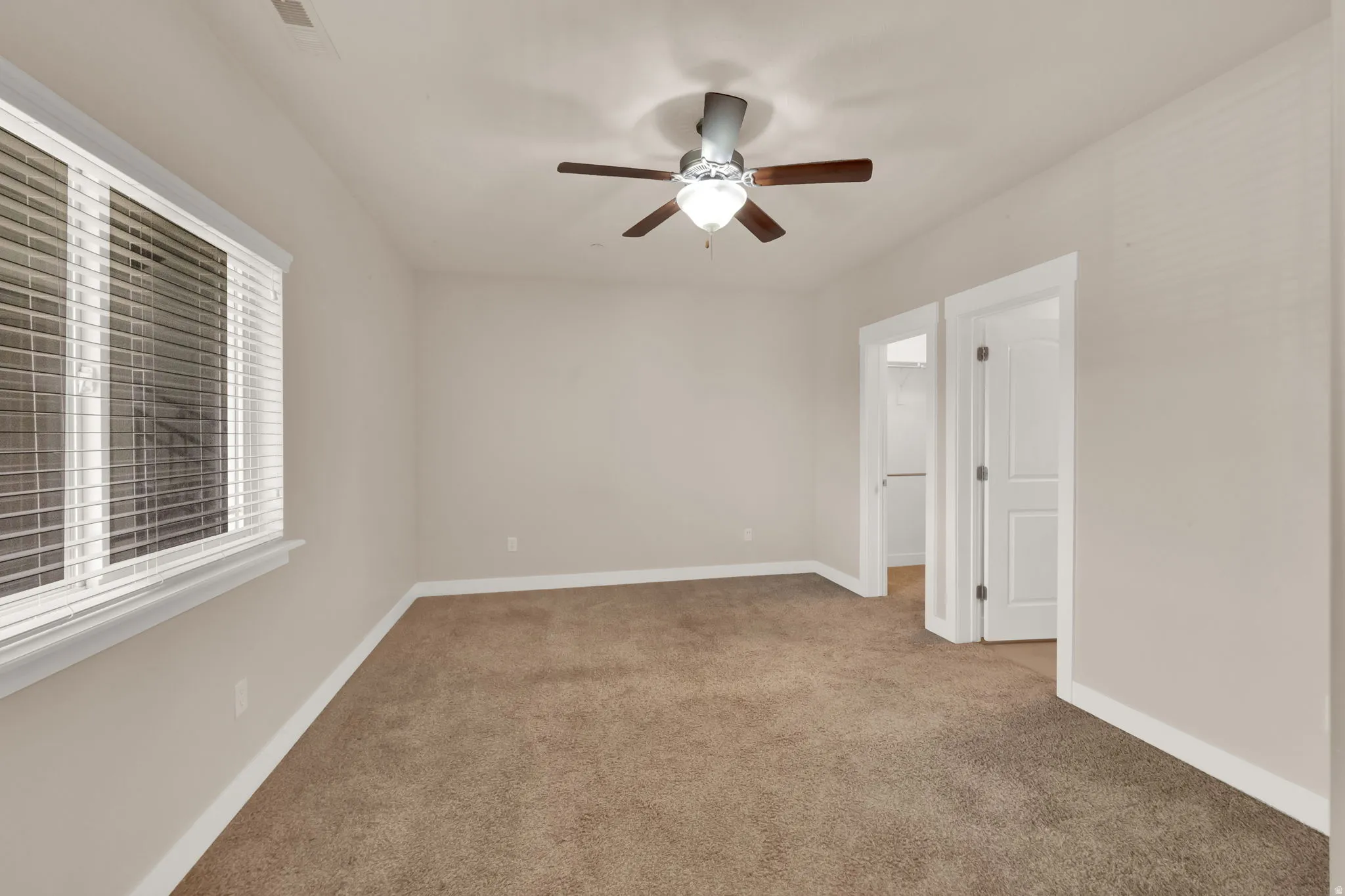 Spare room featuring ceiling fan and light carpet