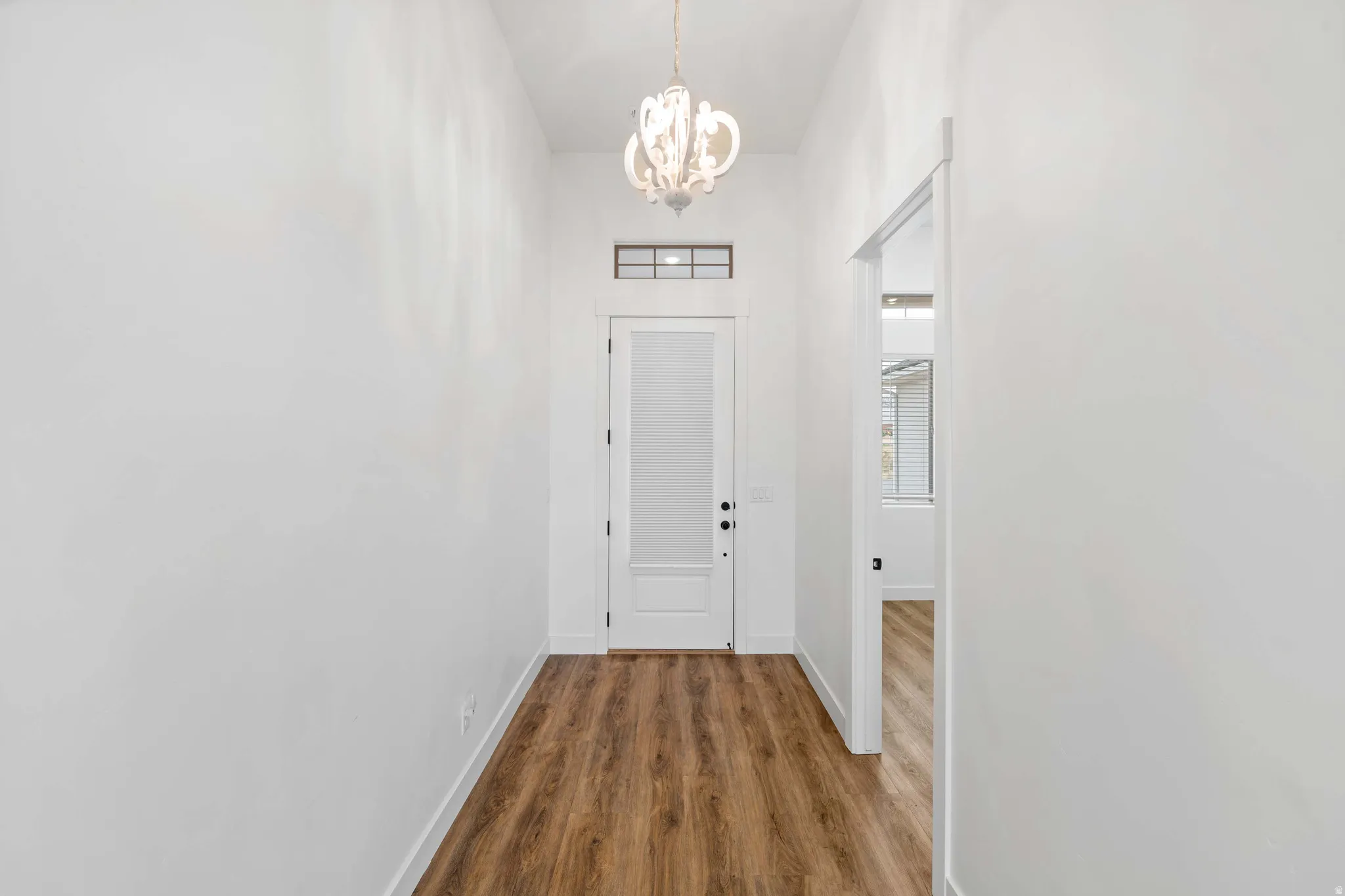 Doorway to outside with a chandelier and wood finished floors