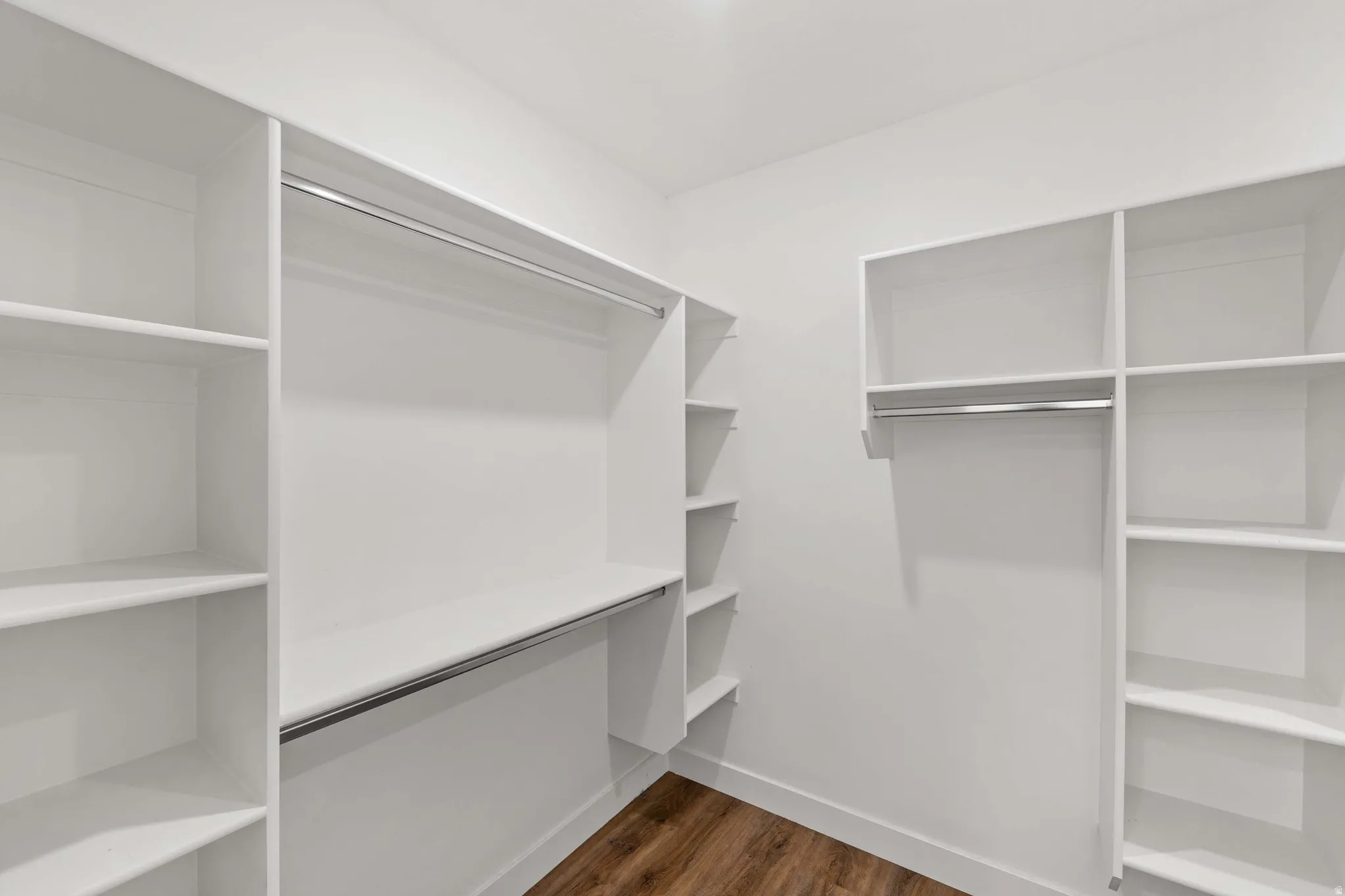 Walk in closet with dark wood finished floors