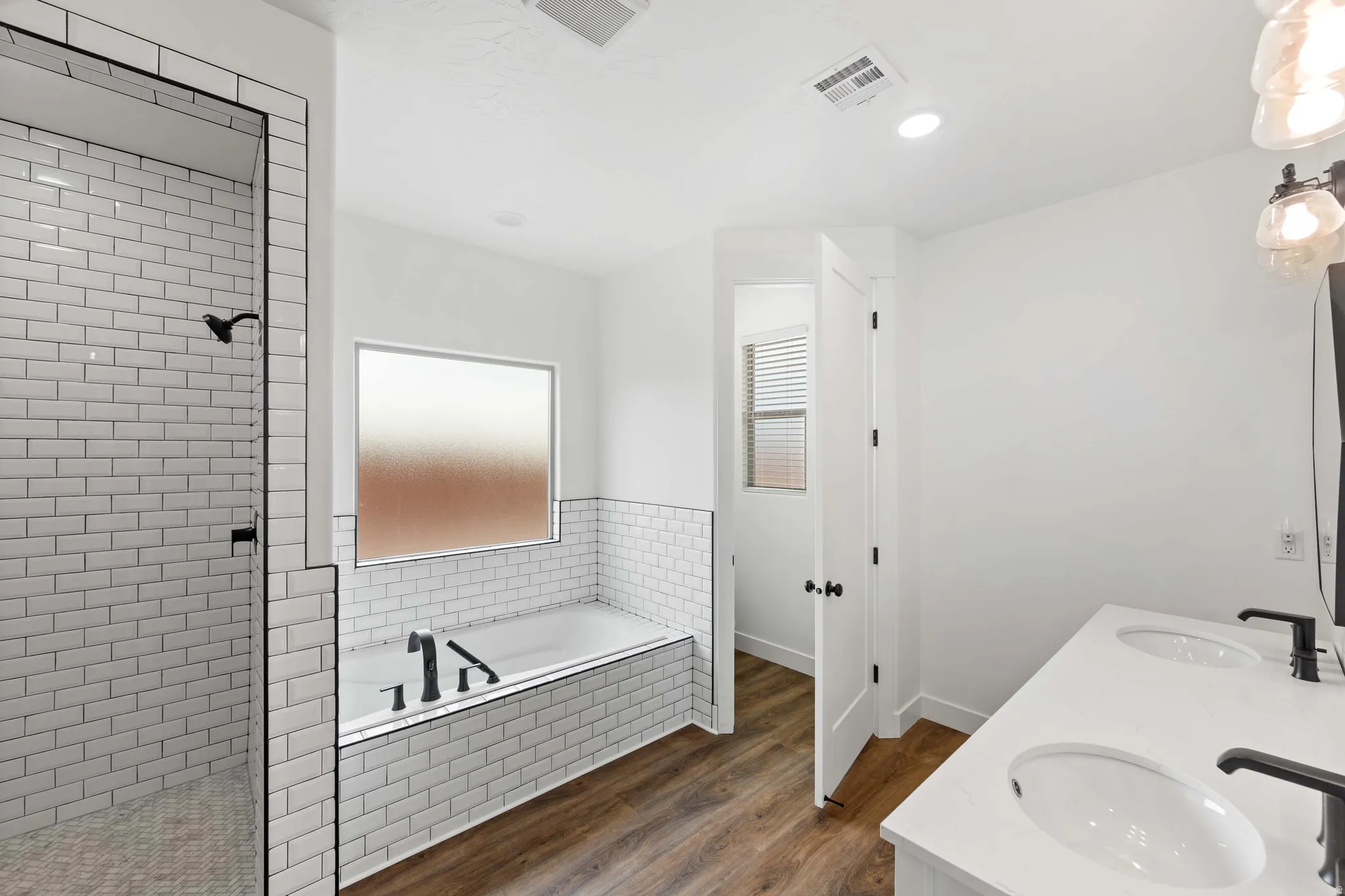 Bathroom featuring dark wood finished floors, a garden tub, walk in shower, double vanity, and recessed lighting