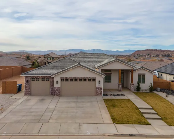 Ranch-style house featuring an attached garage, concrete driveway, stucco siding, covered porch, and a mountain view