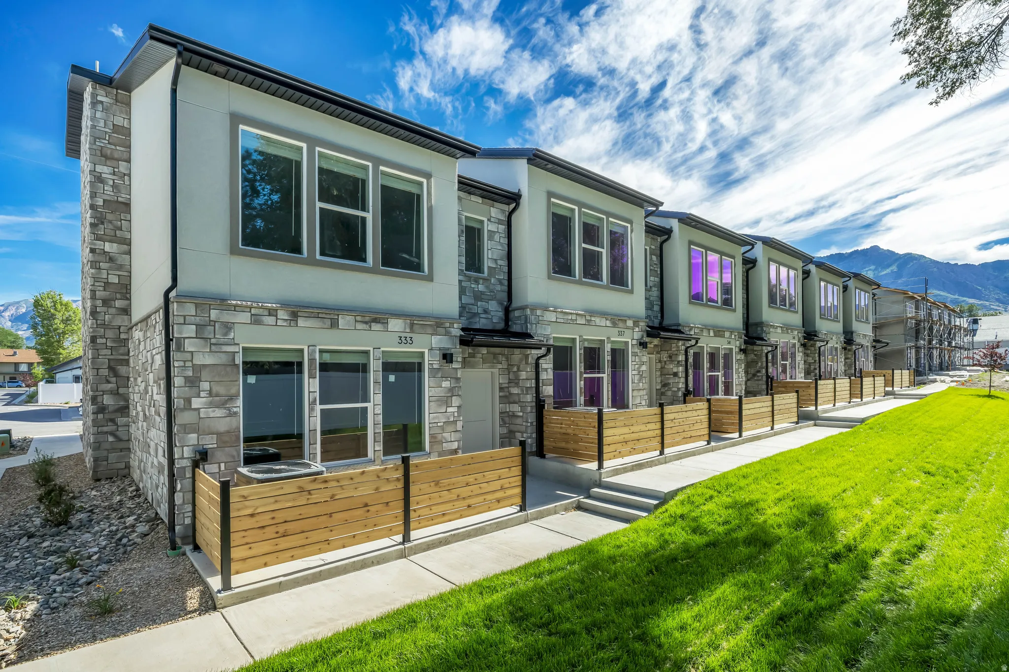 Contemporary townhome exterior featuring stone veneer and light gray siding