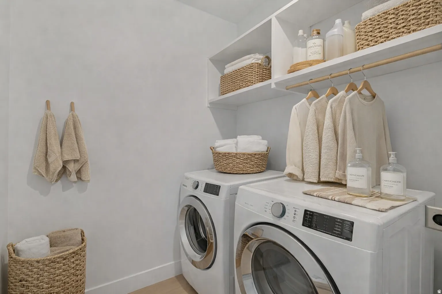 Dedicated laundry area featuring a front-loading washer and dryer, white shelving, and a built-in hanging rod
