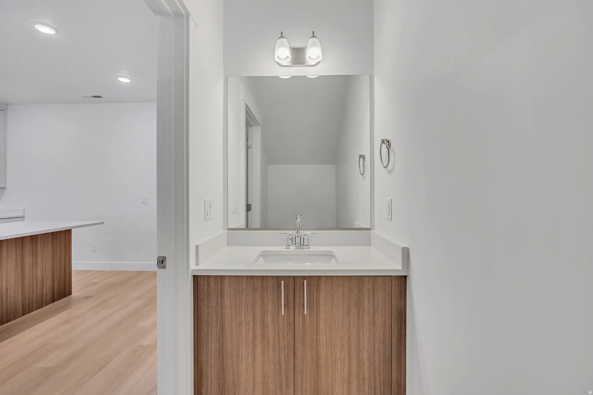Modern vanity with wood-finish cabinetry, white countertop, and integrated sink