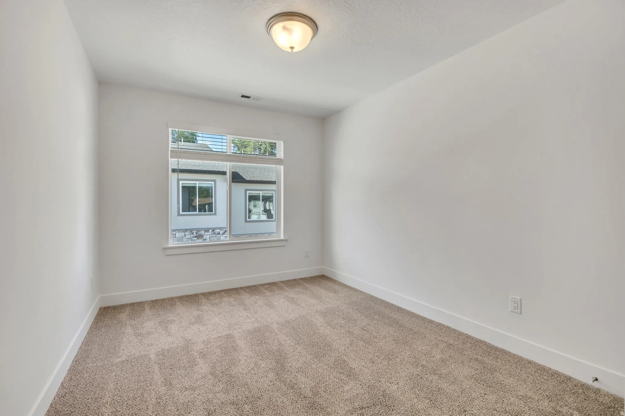 Carpeted room with a ceiling-mounted light fixture and a single window