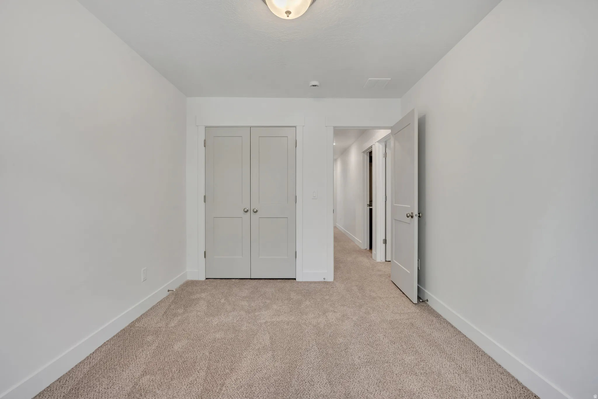 Neutral tone carpet flooring with white baseboards and walls