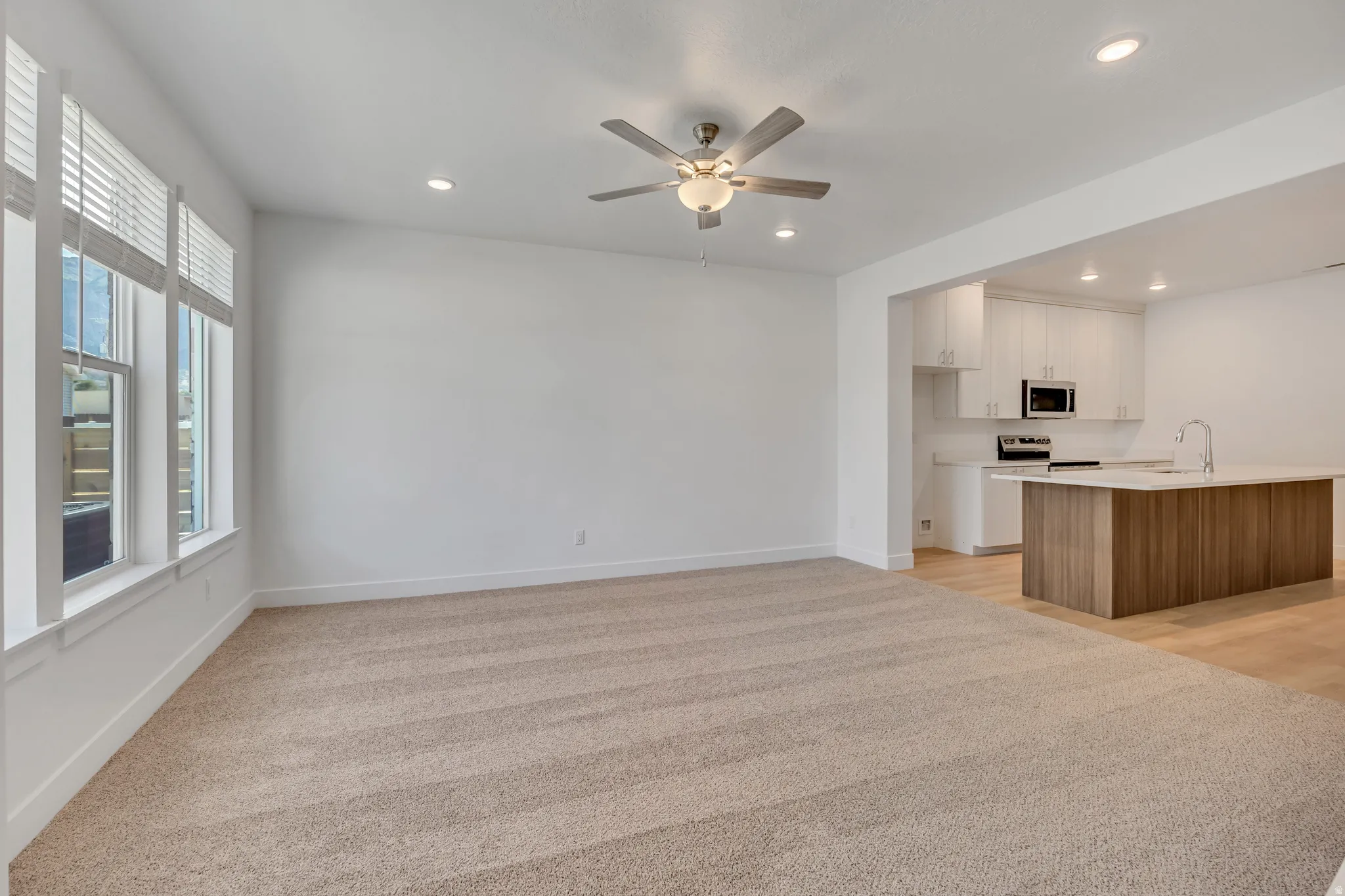 Open-concept living area featuring light-toned carpeting and recessed lighting