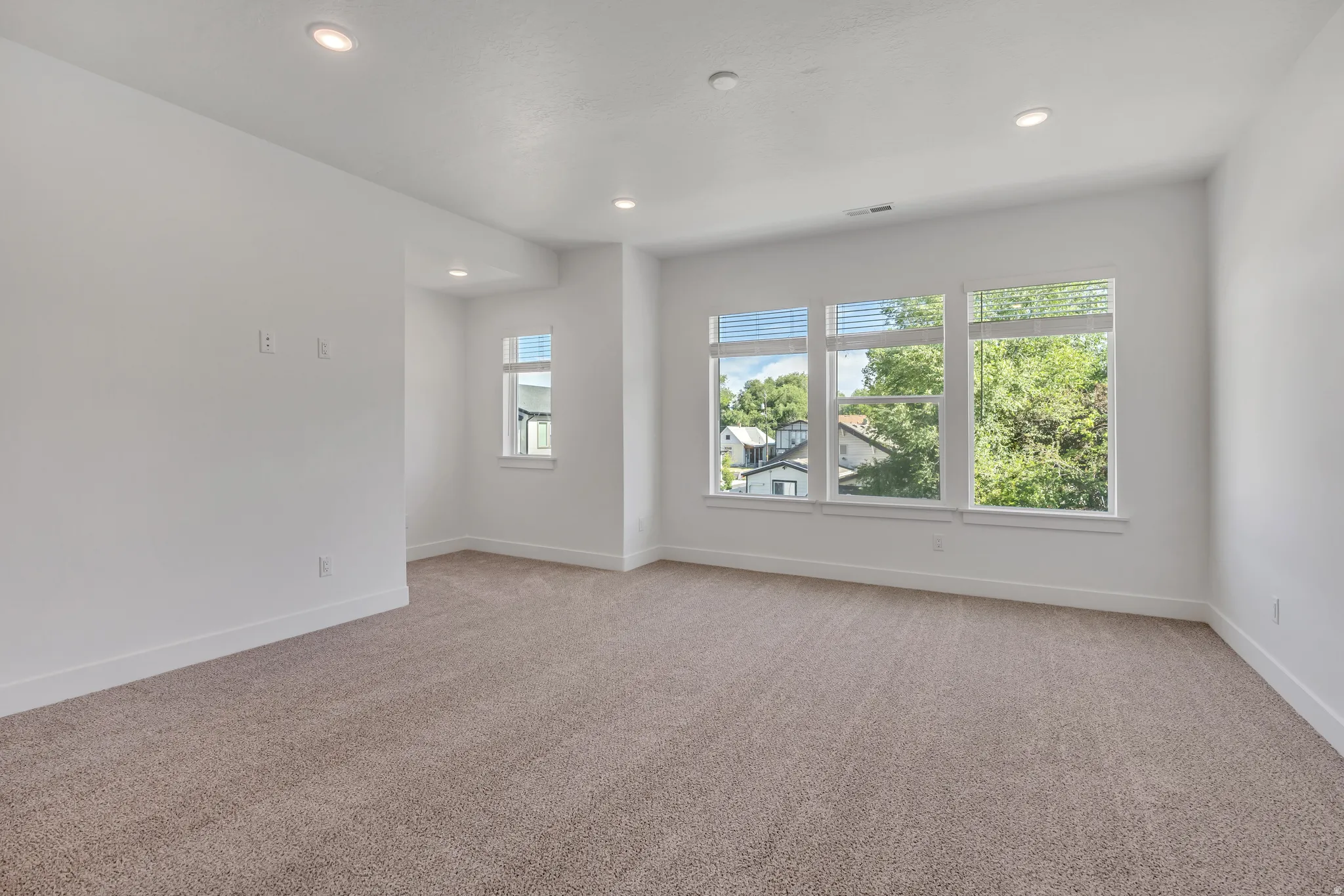 Spacious room with plush carpeting, recessed lighting, and multiple windows