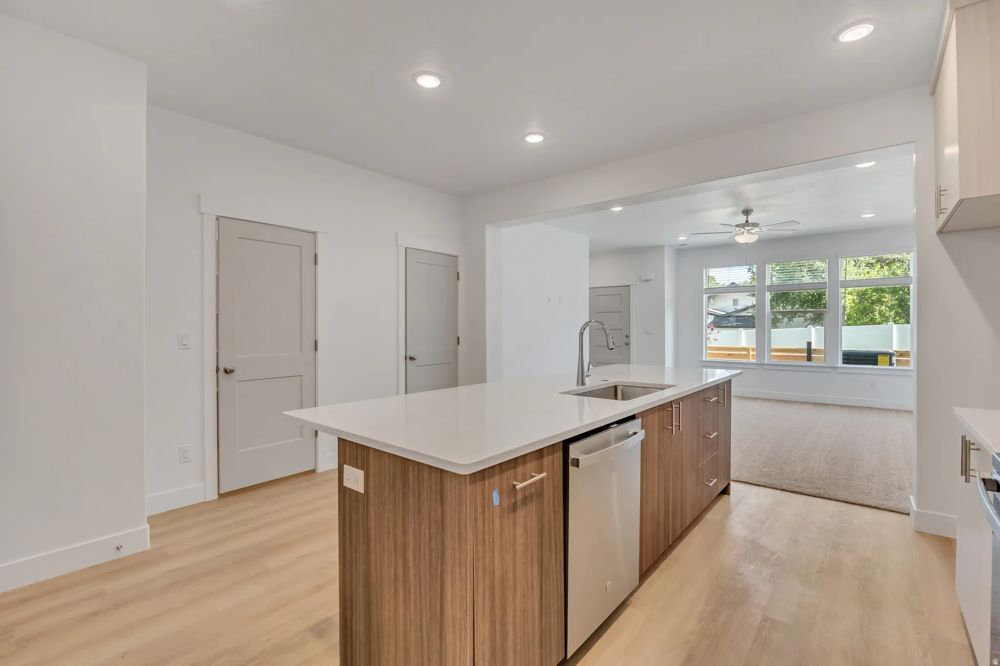 Modern kitchen island featuring a white countertop, undermount sink with a gooseneck faucet, and integrated dishwasher