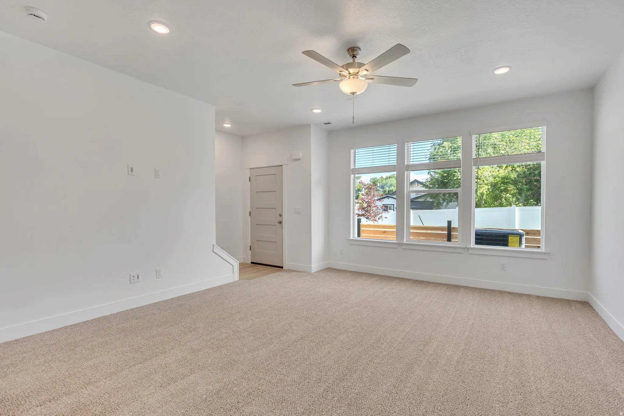 Spacious living area featuring light-toned carpeting, white walls, and recessed lighting