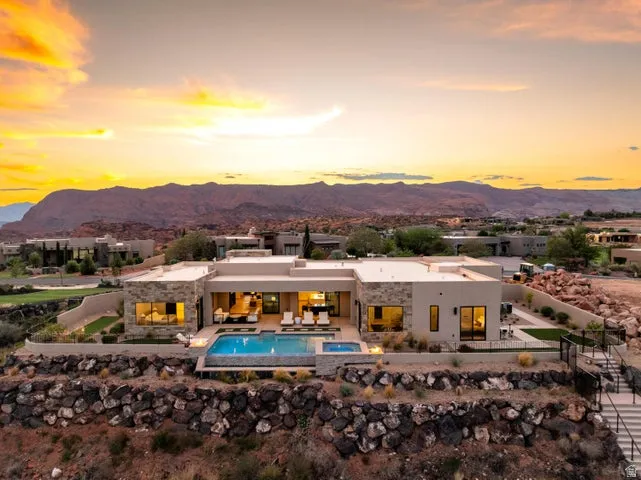 Back of property with a patio area, an infinity pool, a fenced backyard, a mountain view, and stucco siding