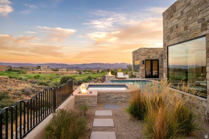 Pool at dusk with an in-ground hot tub, a patio area, and a mountain view