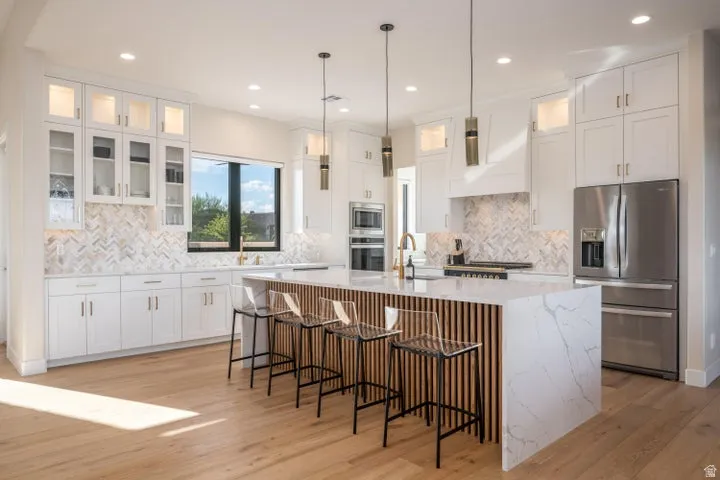 Kitchen featuring glass fronted cabinets, white cabinets, and stainless steel appliances