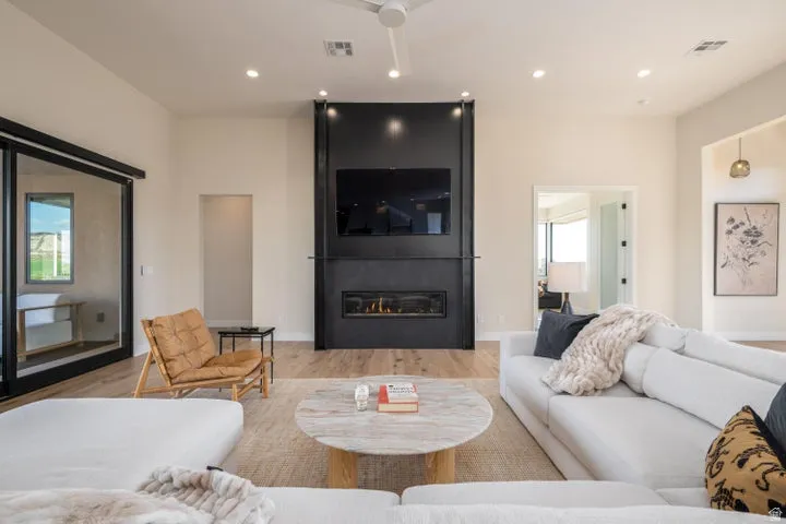 Living room with light wood finished floors, a large fireplace, and recessed lighting