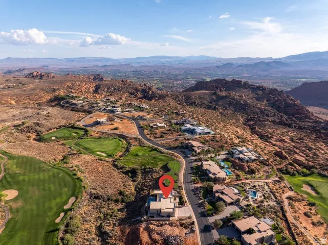 Aerial perspective of suburban area featuring a golf course and a mountainous background