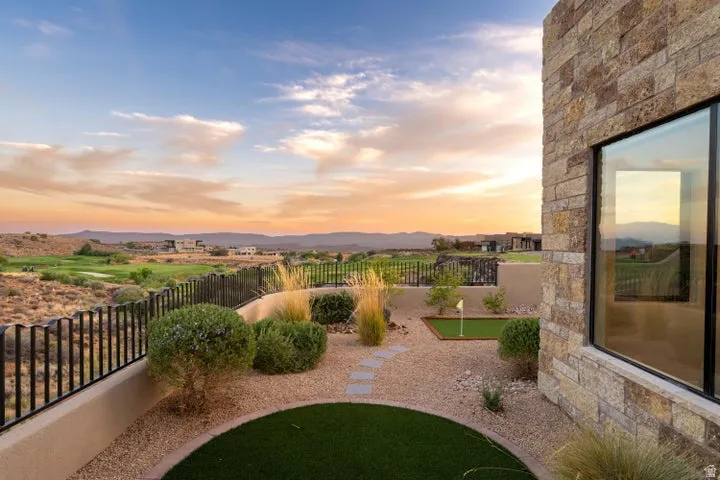 Yard at dusk featuring a fenced backyard, an area to practice putting, and a mountain view
