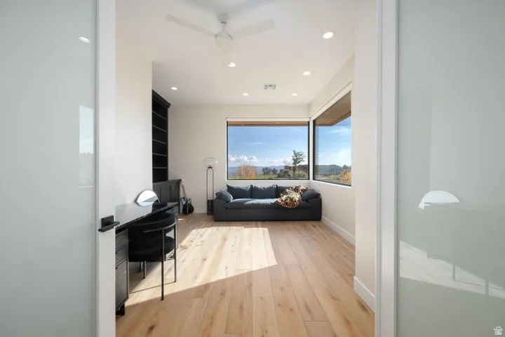 Sitting room with light wood finished floors, recessed lighting, a ceiling fan, and built in desk