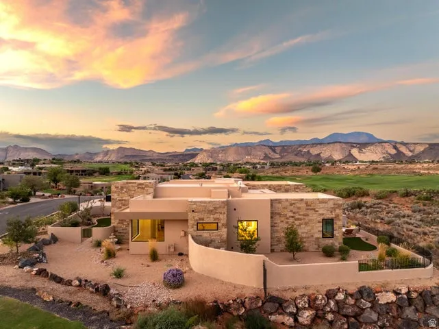 Pueblo revival-style home with stucco siding, a mountain view, and stone siding