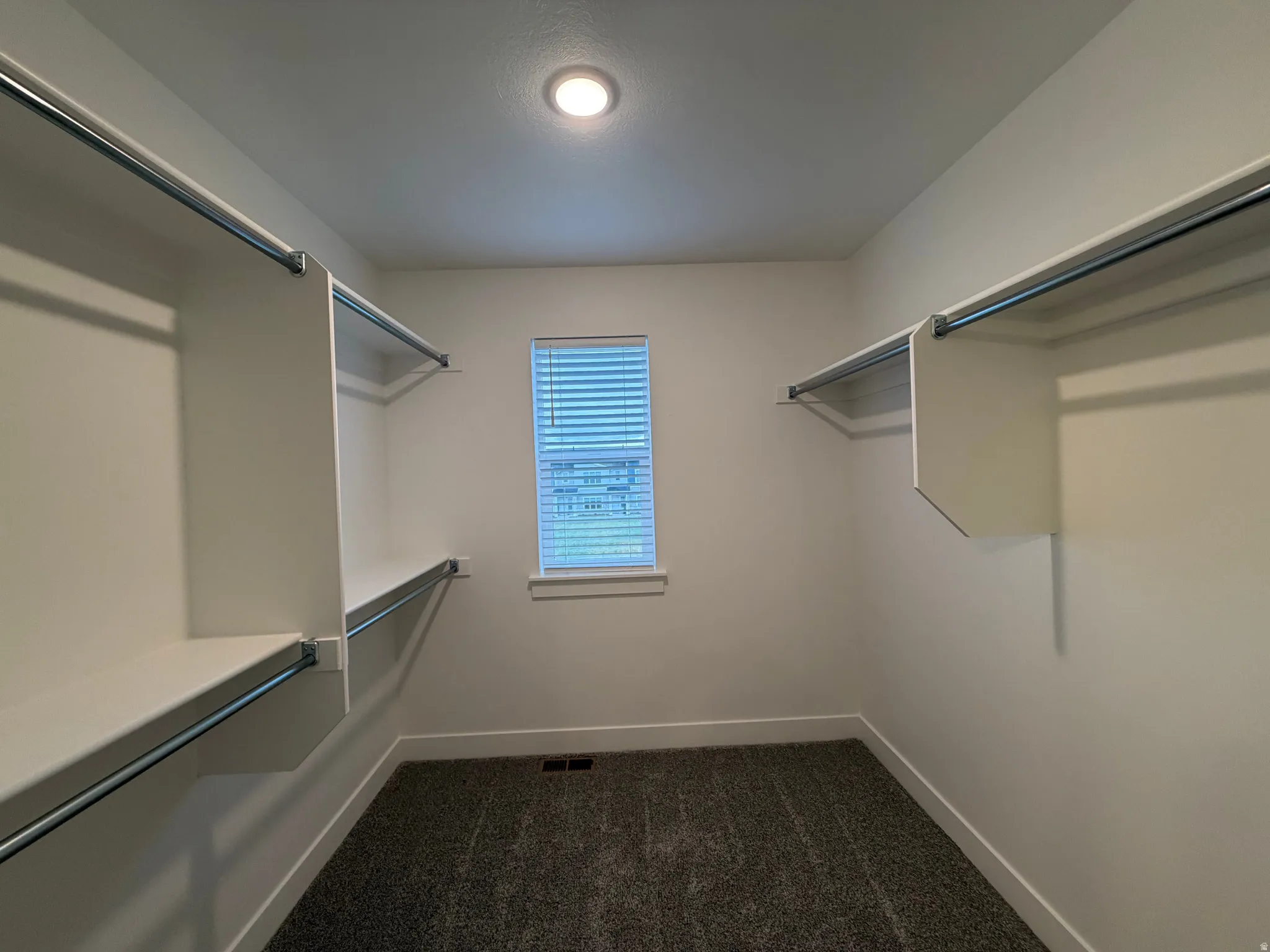 Premier bedroom's large walk in closet with dark colored carpet