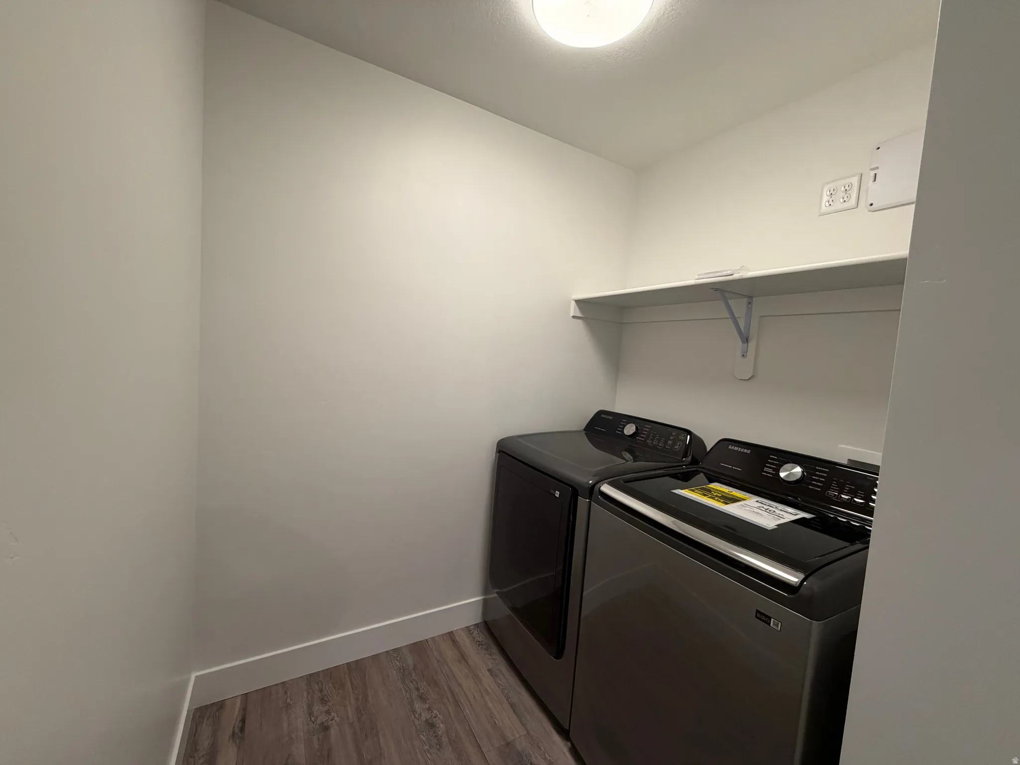 Laundry area with dark wood-type flooring and washing machine and dryer