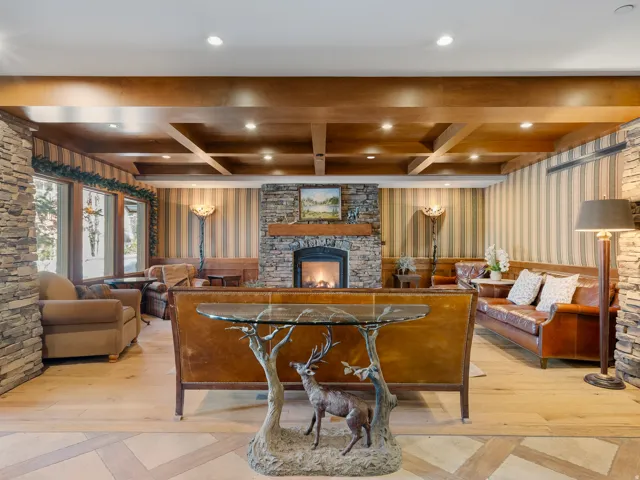 Lobby of Powderhorn. Living room with a stone fireplace, wallpapered walls, light wood finished floors, coffered ceiling, and recessed lighting