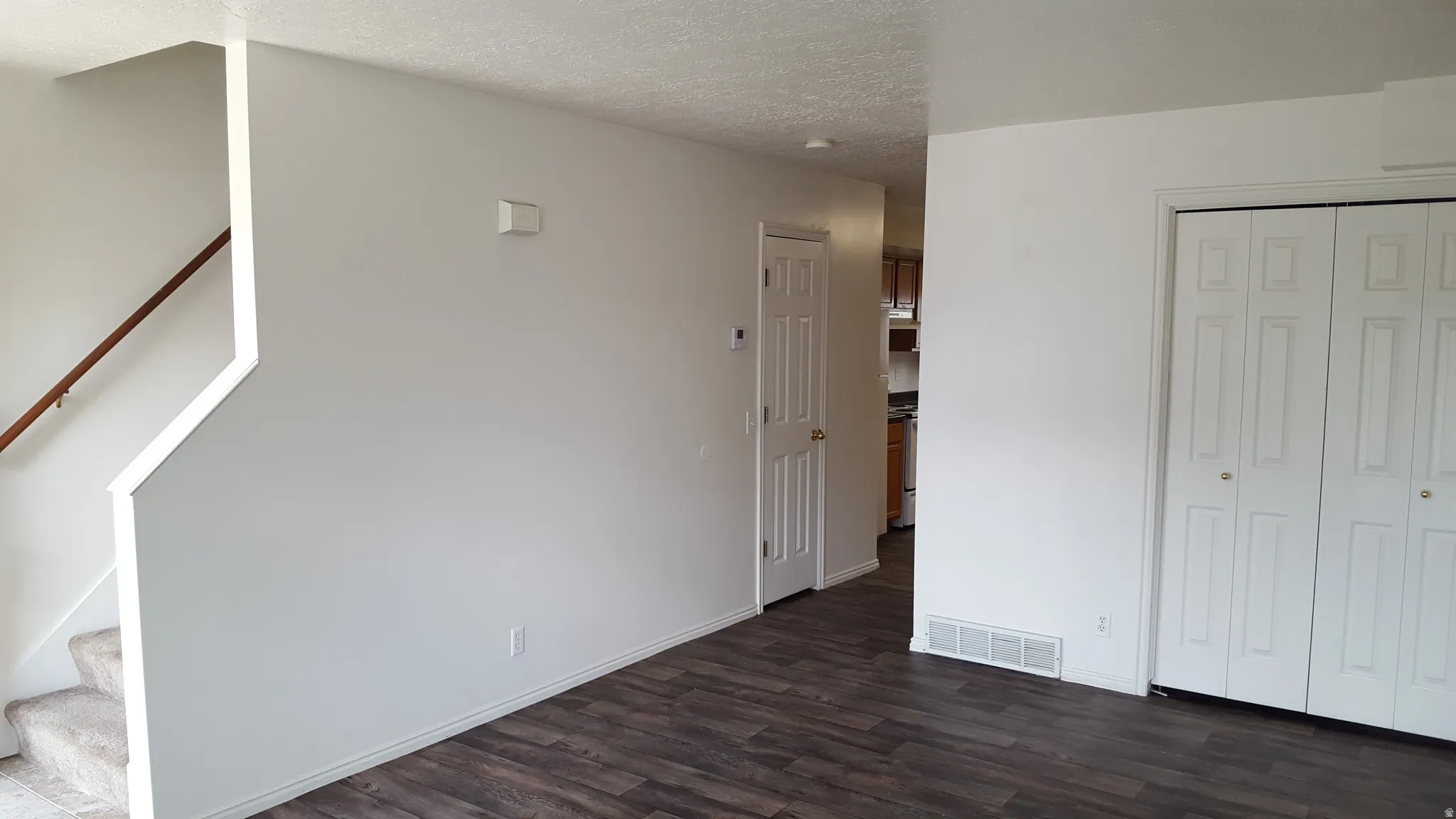 Unfurnished bedroom with dark wood-style floors, a textured ceiling, and a closet