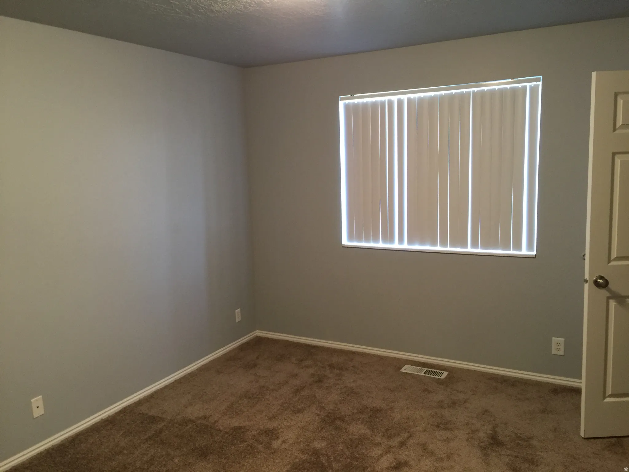Empty room with dark carpet and a textured ceiling