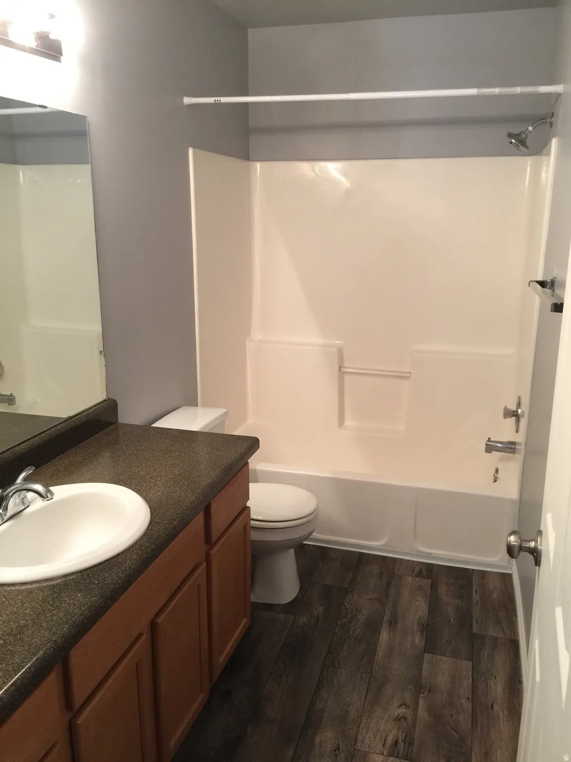 Full bath with shower / bathtub combination, vanity, and dark wood-type flooring
