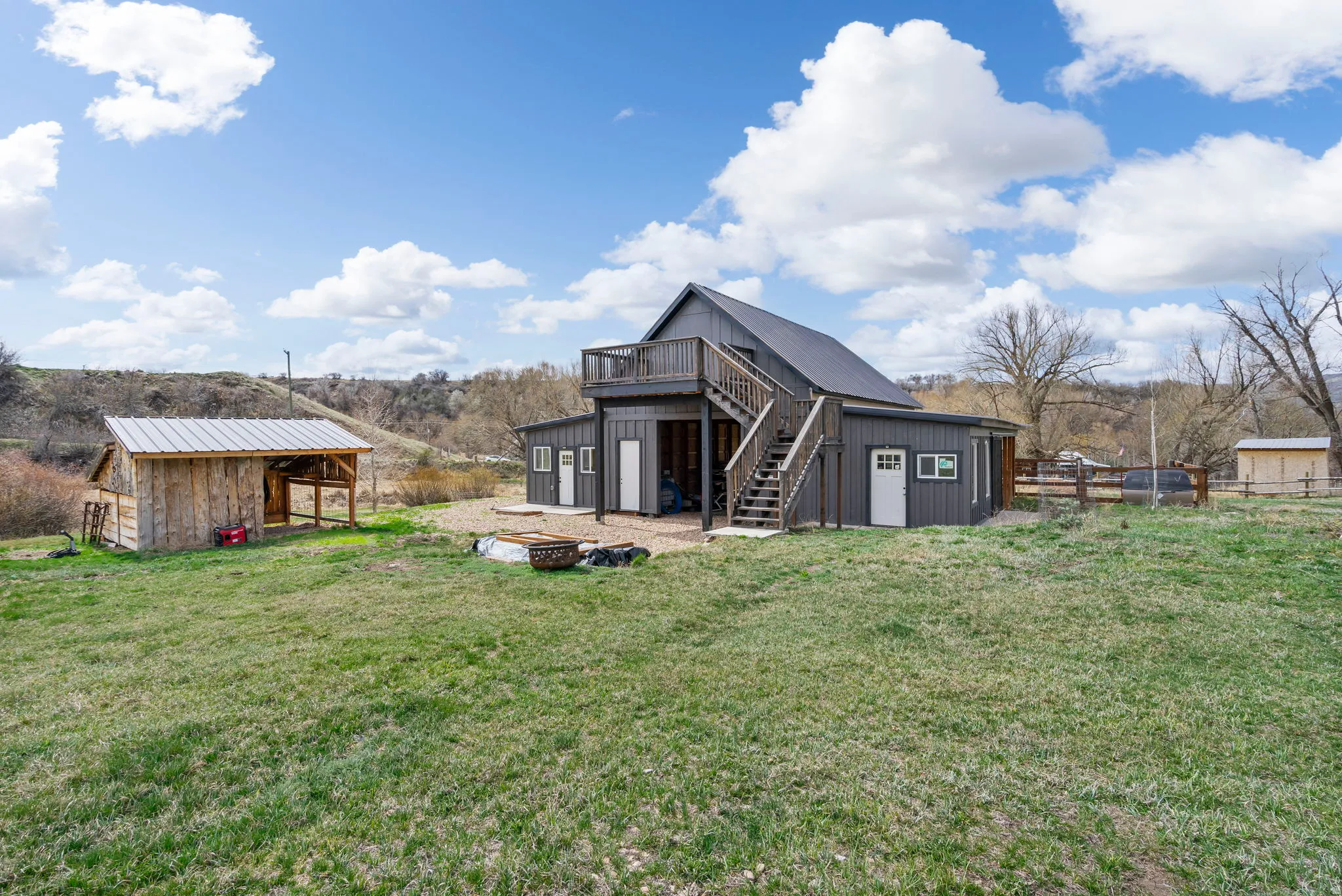 Rear view of house featuring an outdoor fire pit, an outbuilding, a deck, and a metal roof